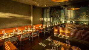 A restaurant interior with wooden booths, tables set for dining, and a large mural of birds on the wall. - Check in with a Cocktail | Heart of Hermosa Beach (Hermosa Beach)