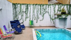 En swimmingpool med solstolar och en krukväxt.