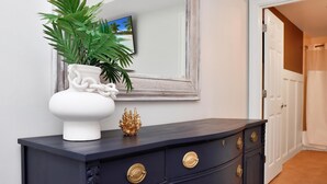 Une commode en bois foncé avec des poignées dorées, un vase blanc contenant une plante et un objet décoratif doré.