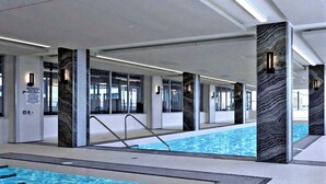 Piscina interna com água cristalina, rodeada por colunas com padrão texturizado.