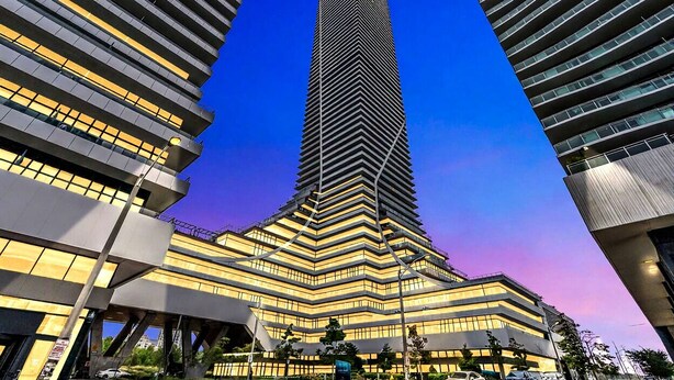 Um arranha-céu moderno com um design em zigue-zague, rodeado por outros edifícios contemporâneos.