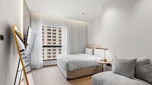 Een moderne hotelkamer met een bed, een bank, een lamp en een schilderij aan de muur.