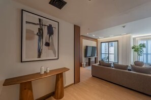 Ein modernes Wohnzimmer mit einer großen Couch, einem hölzernen Konsolentisch und einem gerahmten abstrakten Gemälde.