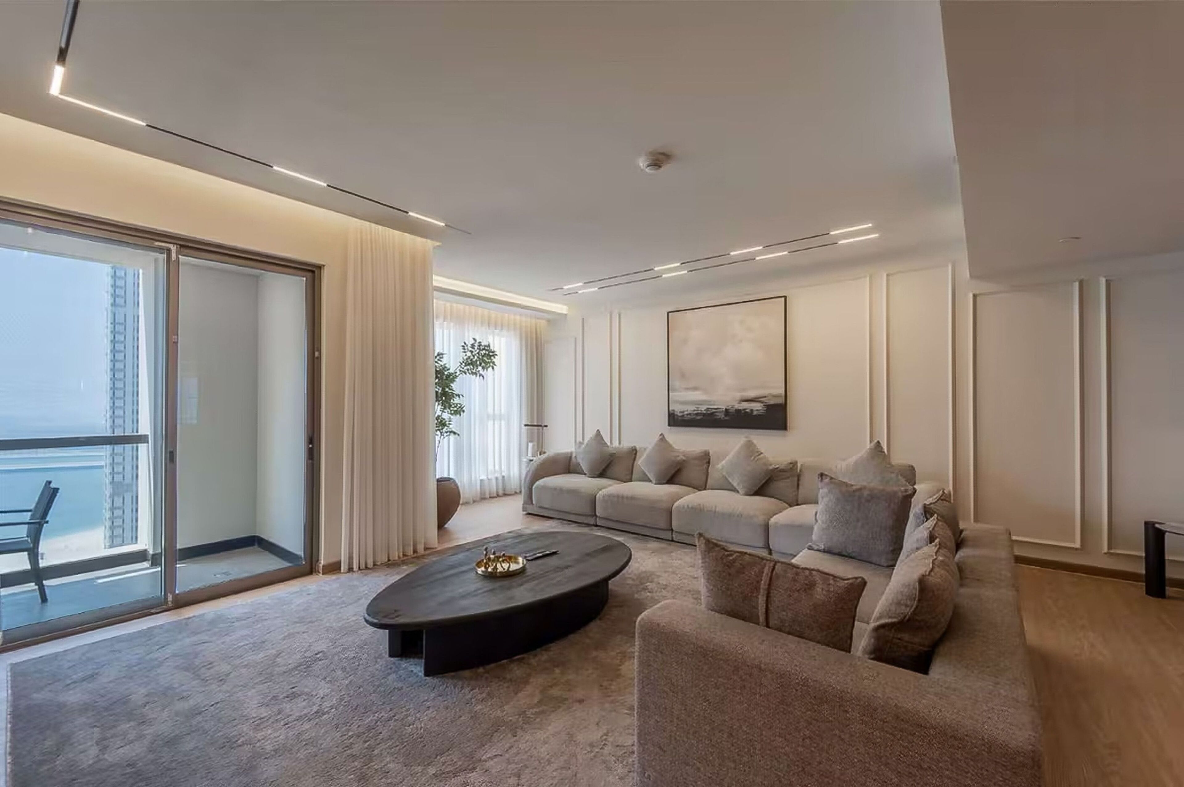 A modern living room with a sofa, a coffee table, and a large window with a view of a building.