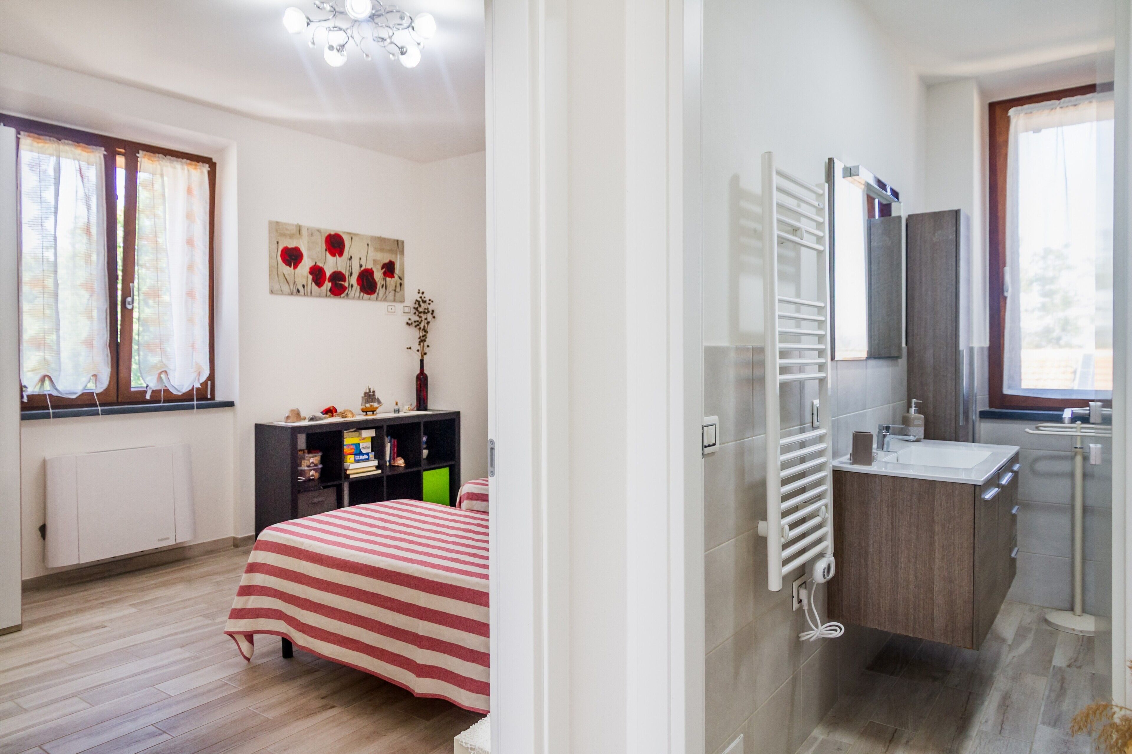 Een slaapkamer met een bed, een kast, een radiator en een raam met gordijnen.