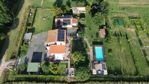 An aerial view of a residential area with a house featuring solar panels, a swimming pool, and a well-maintained lawn. - Podere 660 – Il Giuggiolo Apartment (Grosseto)