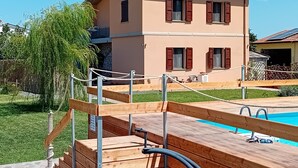 Un bâtiment à deux étages doté d’une piscine, d’une terrasse en bois et d’une barrière en corde.