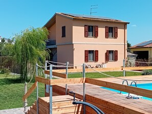 Un bâtiment à deux étages doté d’une piscine, d’une terrasse en bois et d’une barrière en corde.