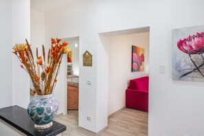 Et moderne interiør med en vase med tørrede blomster på en sort overflade, en rød stol og et maleri på væggen.