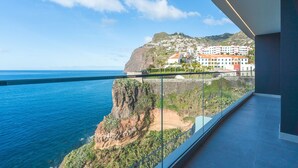 Un balcón con vistas a un pueblo costero, un acantilado y el mar.