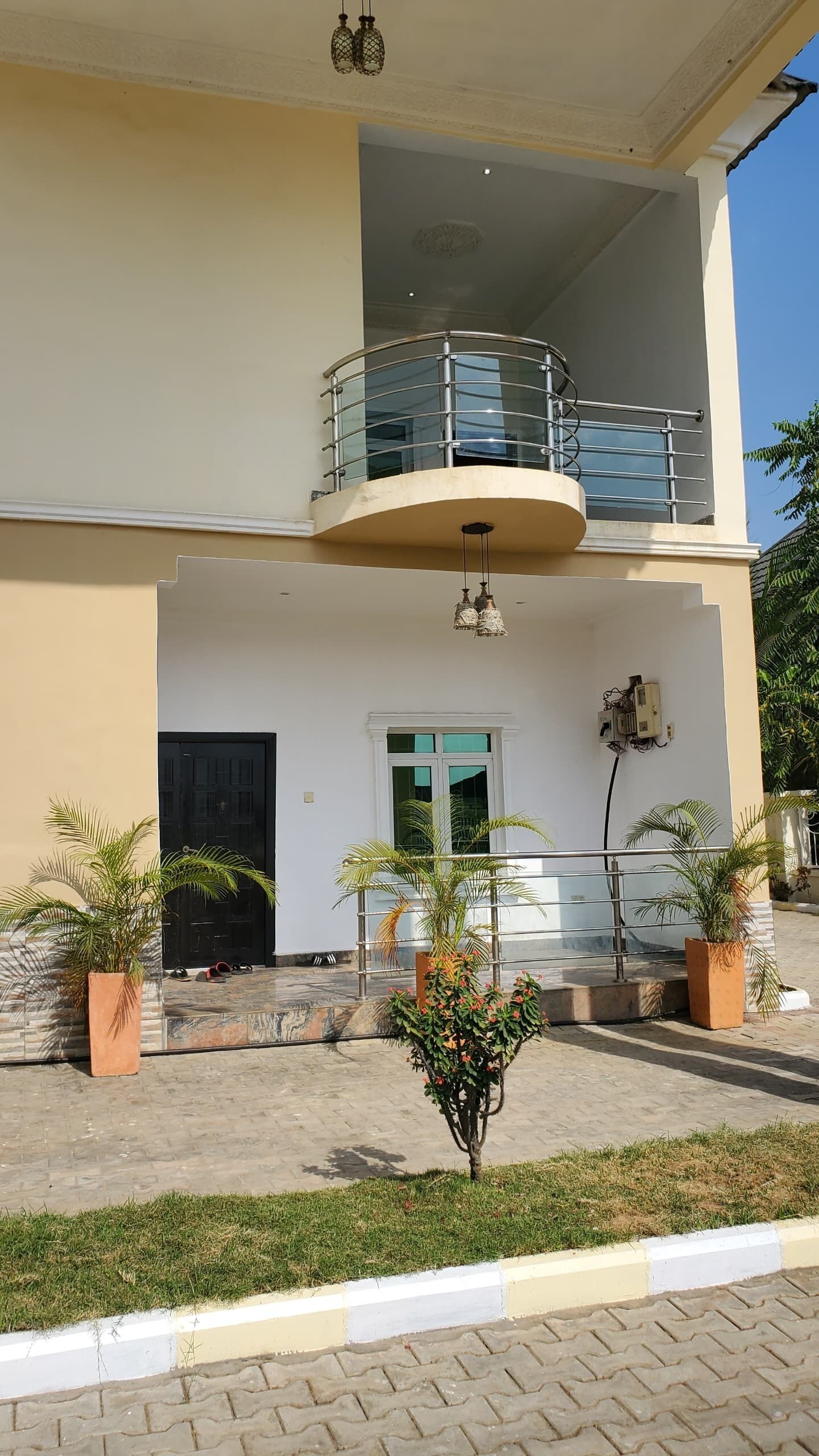 A two-story building with a balcony, a door, and potted plants.