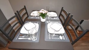 A dining table set with place settings, a vase with flowers, and a glass of water. - Benbow Suite (Hinton)