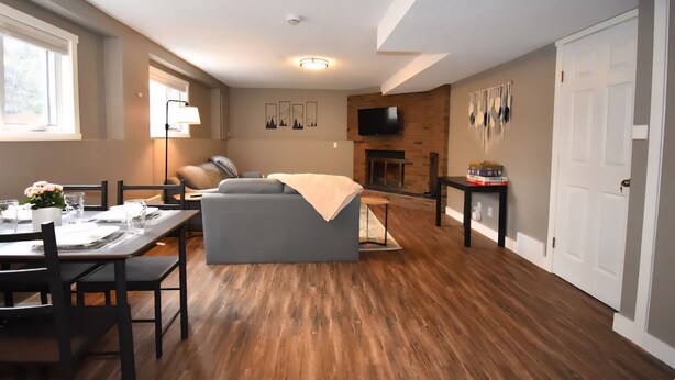 A modern living room with a sofa, dining table, and a fireplace. - Benbow Suite (Hinton)
