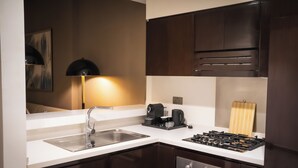 A modern kitchen with a stainless steel sink, a coffee maker, a gas stove, and dark wooden cabinets. - Modern 1BR Downtown - Dubai Mall Walk (Dubai)