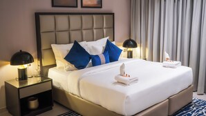 A neatly made bed with white and blue bedding, a headboard, and a nightstand with a lamp. - Modern 1BR Downtown - Dubai Mall Walk (Dubai)
