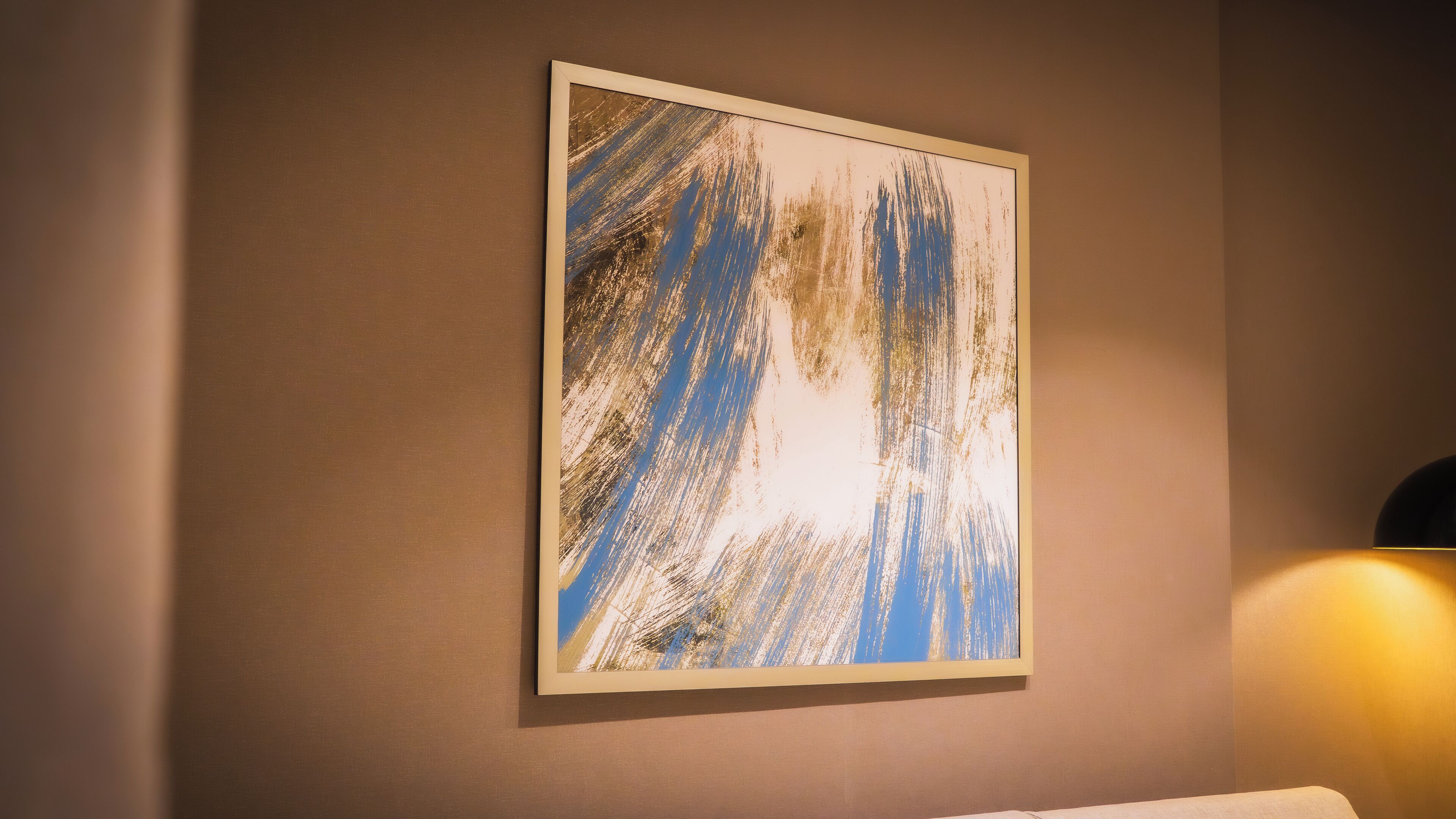 A framed abstract painting on a wall in a hotel room.