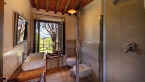 Un bany amb una banyera independent, un vàter, un bidet i una dutxa amb envàs de vidre.