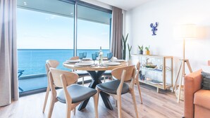 A modern dining area with a large window overlooking the sea, a round table with chairs, and a glass cabinet with decorative items. - Xavelha Clifftop by Atlantic Holiday (Camara de Lobos)