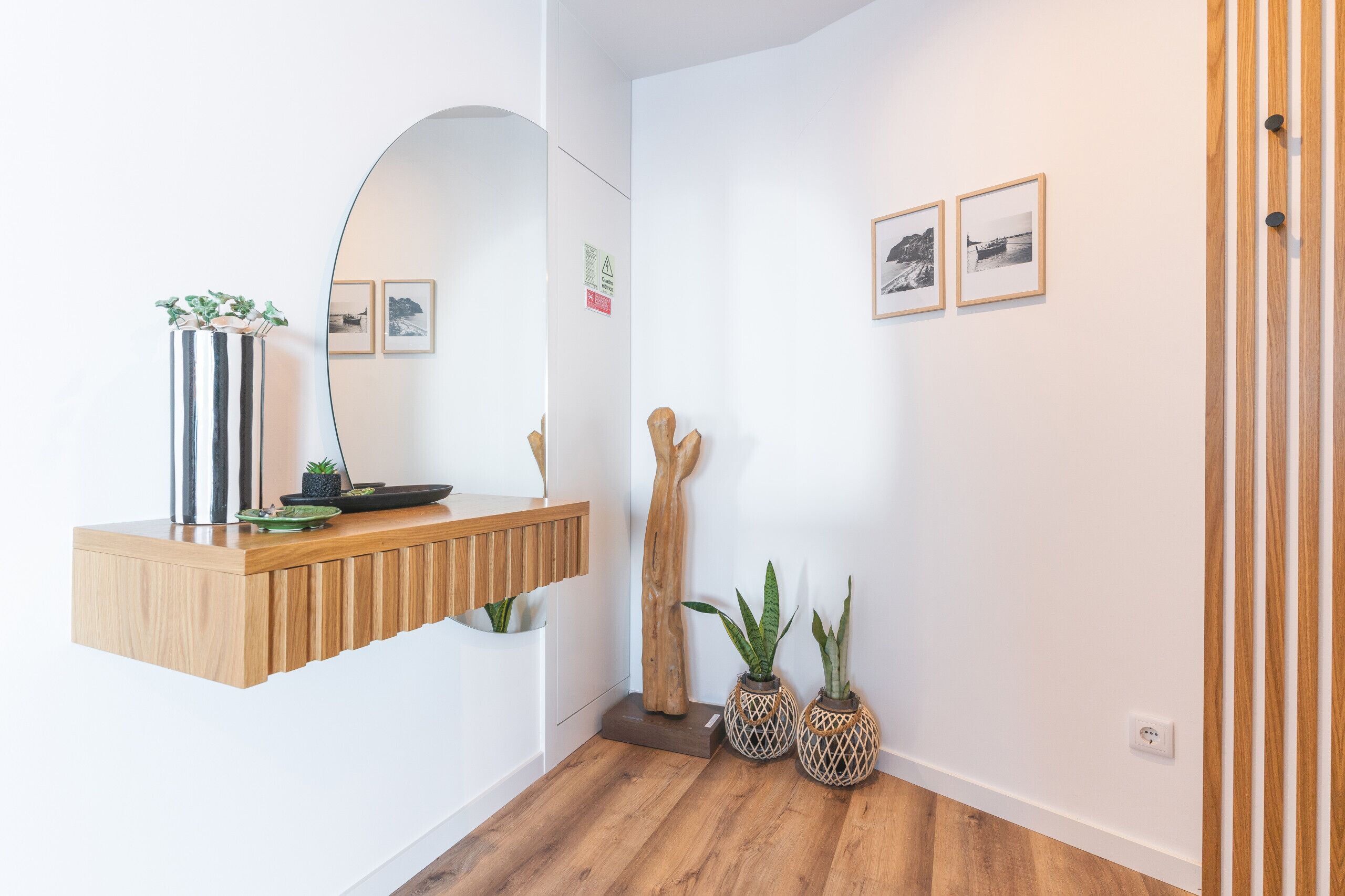 Un interno moderno con una scrivania di legno per la reception, uno specchio, quadri incorniciati e due piante in vaso.