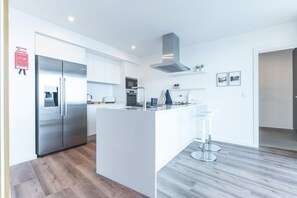 Eine moderne Küche mit weißen Schränken, Edelstahlgeräten und einer zentralen Kochinsel mit Barhocker.