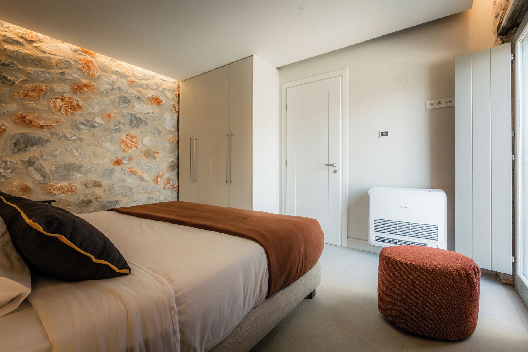 Un dormitorio con cama, armario, puerta y aire acondicionado.