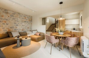 Un salon moderne avec un mur en pierre, un canapé, une table basse et un coin repas avec des chaises.