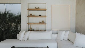 Un soggiorno moderno con un divano bianco, un tavolino in legno e una libreria a muro con oggetti decorativi.