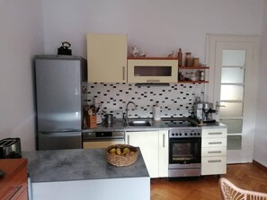 Een kleine keuken met een koelkast, magnetron, fornuis en spoelbak.