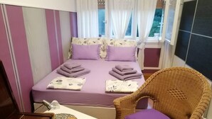 Una camera da letto con un letto, una sedia, un tavolo e una finestra con tende.