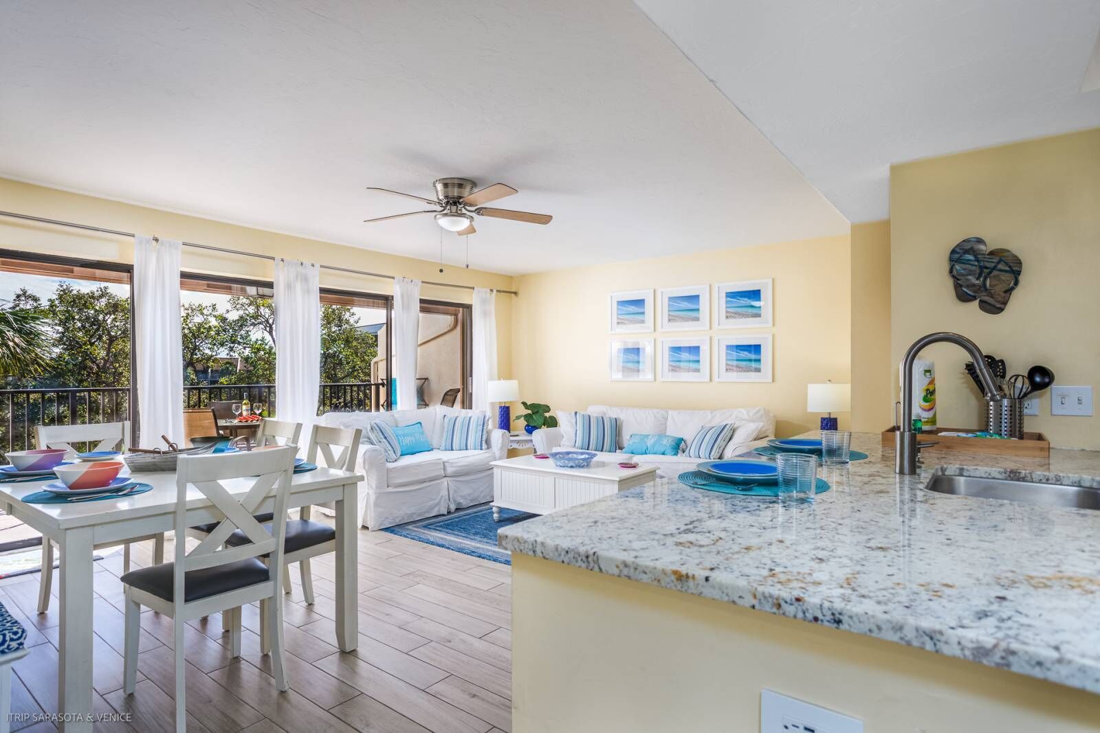 A spacious living area with a balcony, a dining area, and a kitchen with granite countertops.