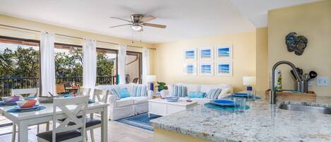 A spacious living area with a balcony, a dining area, and a kitchen with granite countertops.
