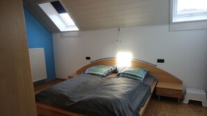 A bedroom with a single bed, a nightstand, a drawer, a radiator, and a skylight. - Cozy 2-room apartment in the southern Black Forest (Steinen)