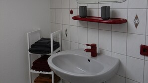 A bathroom with a white sink, red towel rack, and a mirror above the sink. - Cozy 2-room apartment in the southern Black Forest (Steinen)