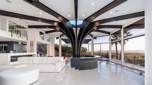 Een modern interieur met een centrale zithoek, een keuken en grote ramen met uitzicht.