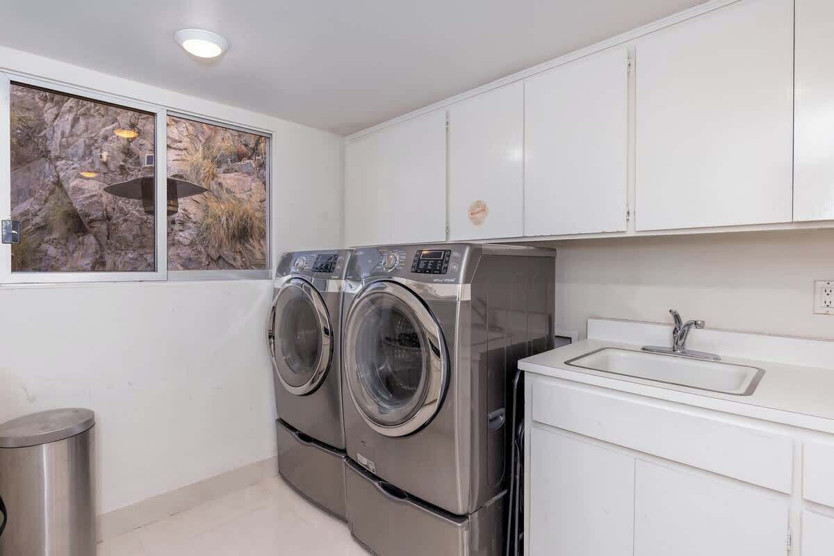 A modern kitchen with stainless steel appliances, a sink, and a window with a rock wall view.