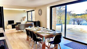 Un coin repas avec une table dressée pour quatre personnes, un téléviseur et un mur en pierre.