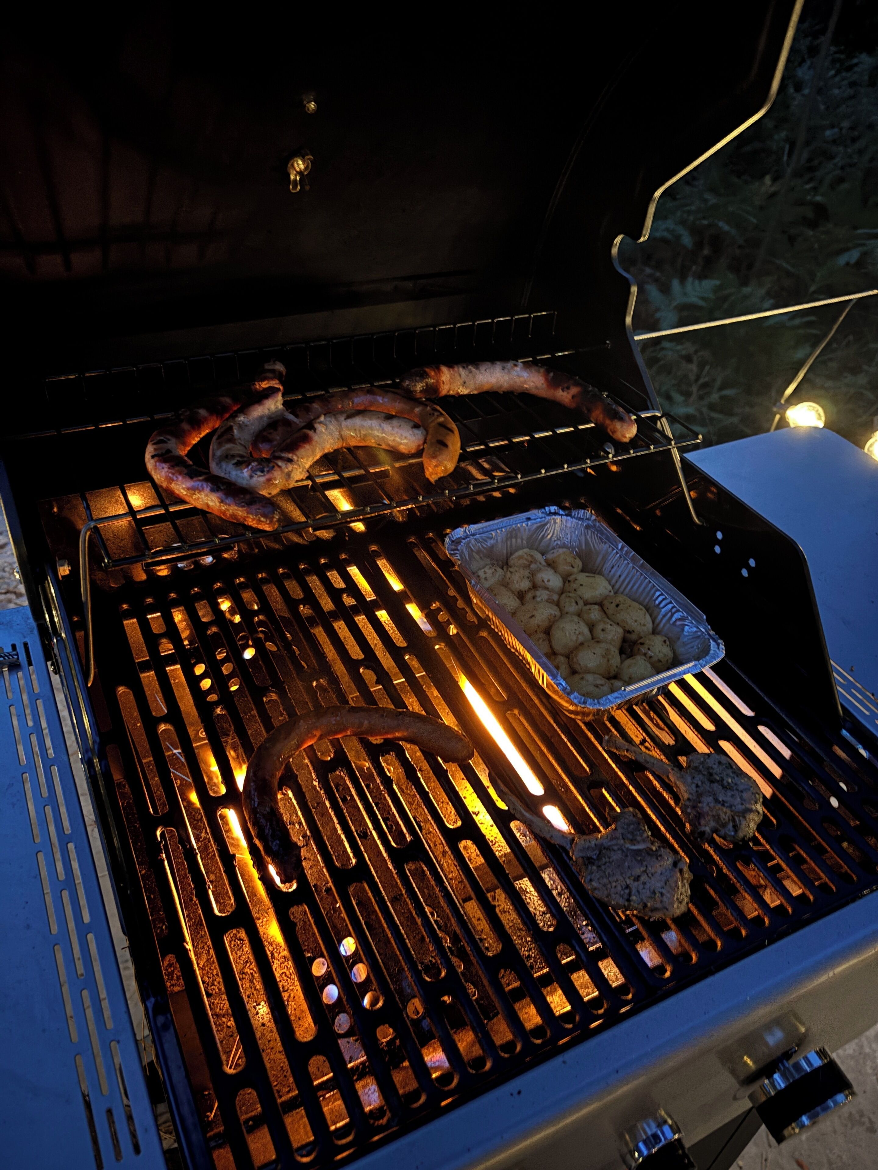 Una parrilla con salchichas y papas.
