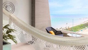 Ein Hängestuhl auf einem Balkon mit Blick auf einen Strand.