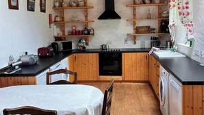 Une cuisine compacte avec des meubles en bois, un îlot central, une table à manger avec des chaises et un lave-linge.