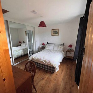 Una camera da letto con un letto grande, due comodini, una sedia, uno specchio e una lampada a soffitto.