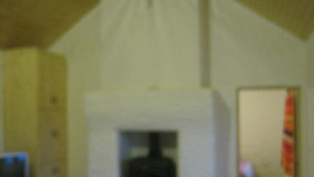 Une pièce avec une cheminée, une porte donnant sur une autre pièce et un couloir visible.
