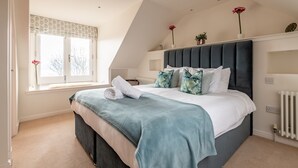 Ein Schlafzimmer mit einem Bett, einem Fenster mit Vorhängen, einem Heizkörper und einem Blumentopf auf dem Fensterbrett.