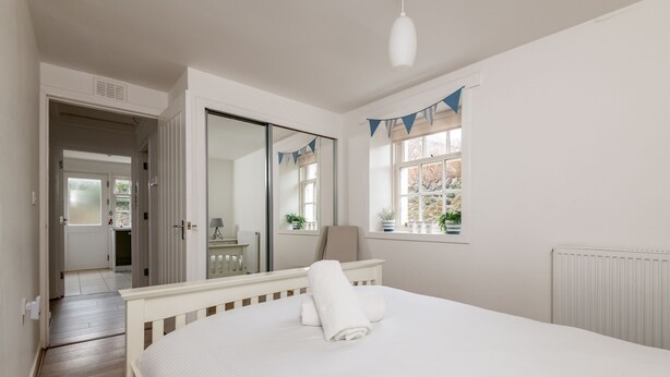 Une chambre à coucher avec un grand lit, une fenêtre avec des rideaux bleus, un miroir et une vue sur l’extérieur.