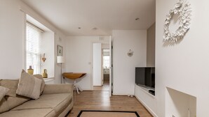 Un salon avec un canapé, un téléviseur et un plancher en bois.