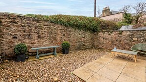 Un mur de pierre avec un banc et des plantes en pot dans une cour.