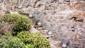 Una escalera de piedra con faroles distribuidos, rodeada de follaje.