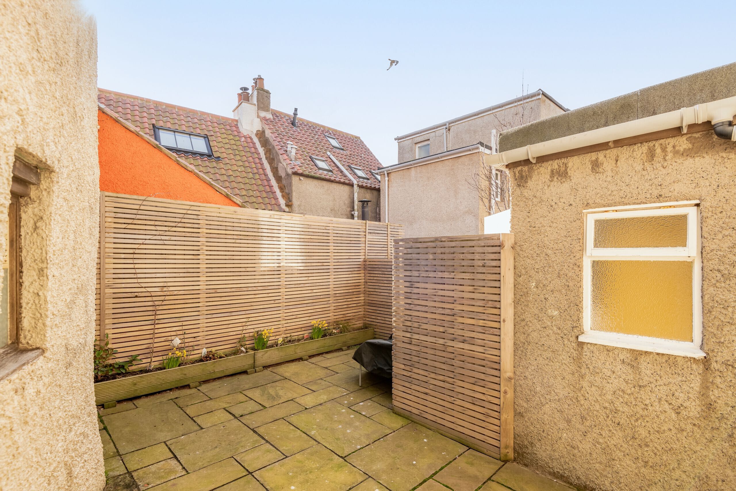 A courtyard with a tiled floor, a wooden fence, and a window.