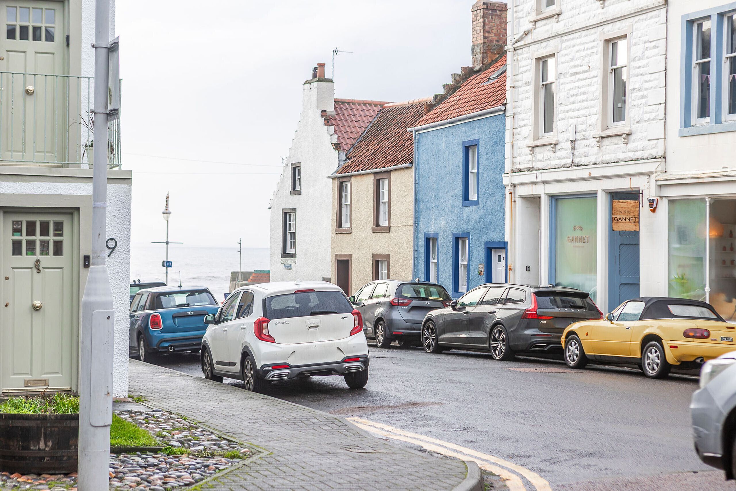 Une rue bordée de voitures garées et d’immeubles.