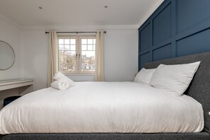 A bedroom with a bed, a desk, and a window with curtains. - Auld Burn Road (No 2) (St Andrews)