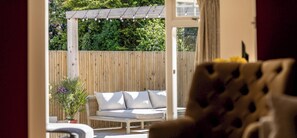 A wooden fence, a white outdoor sofa, and a potted plant. - Auld Burn Road (No 2) (St Andrews)